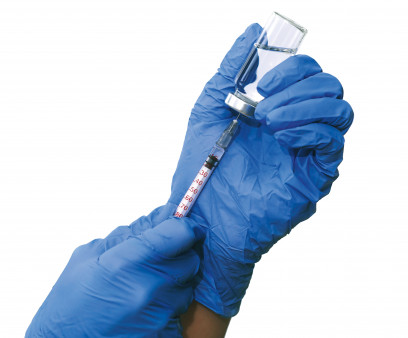 hands with blue gloved filling a syringe from a vial of vaccine