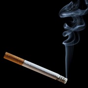 Cigarette with blue smoke on black background