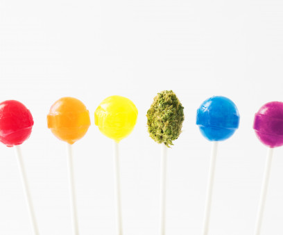Lollipops in the colors of the rainbow, with a green marijuana bud on a lollipop stick in the middle.