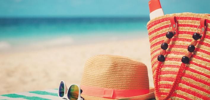 beach bag, sun glasses, sun hat on towel at beach ocean in the background